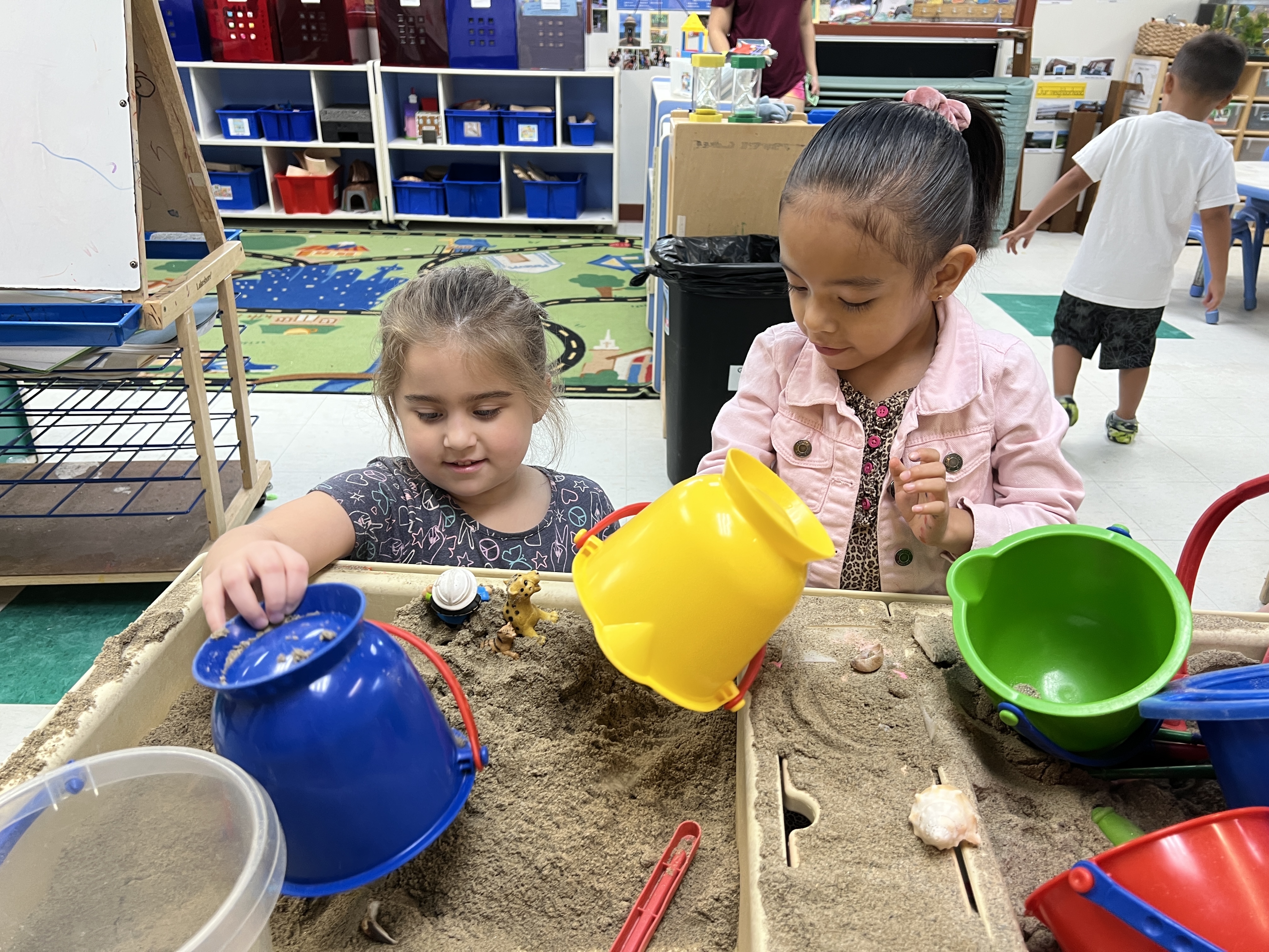 Two preschool students playing together at sand table